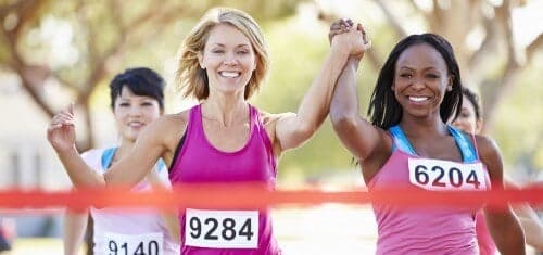 Women finishing a marathon smiling and holding hands
