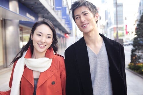 couple smiling at each other walking down street holiday shopping