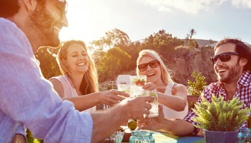 Two couples clink glasses of water together and laugh