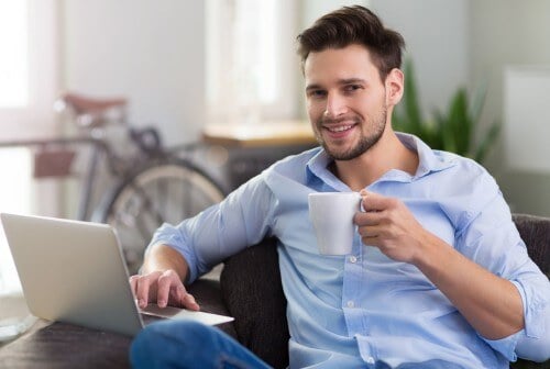Man drinking coffee working on laptop